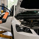 Active Tests vs Live Data on Ediag C1: mechanic holding a phone beside a car with the hood open
