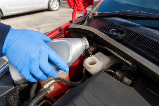 How to use a brake fluid tester and read the results: pouring brake fluid into a reservoir under a red car hood